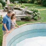 Couple souriant près d'une piscine en été dans le jardin