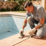 Carreleur professionnel appliquant du joint étanche sur les carreaux d'une piscine en construction pour prévenir les fissures
